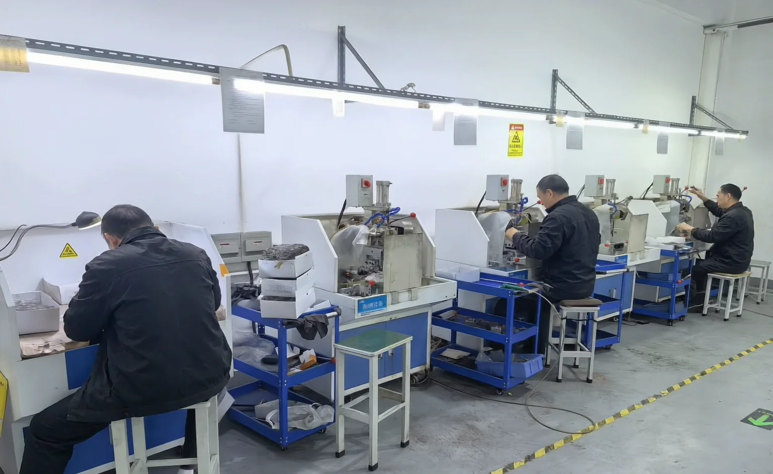 Operators working at individual eyewear production stations